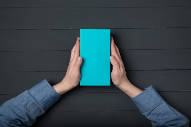 istock Blue box in children's hands on black background. Top view. Flat lay style. 1223521006