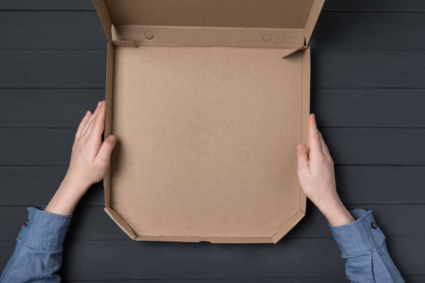 istock Empty open box of pizza in children's hands. Black background. Top view. Copy space. 1223521012