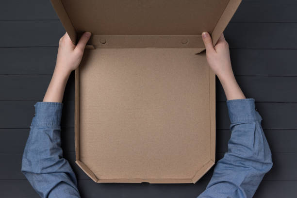 istock Empty open box of pizza in children's hands. Black background. Top view. Copy space. 1223521016