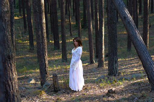 girl in a white dress in the forest at sunset