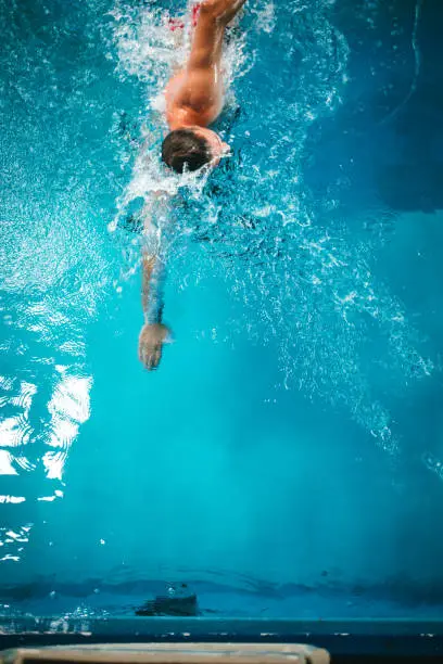 Active mature man swimming at swimming pool, practicing