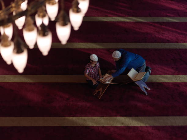 father and son in mosque praying and reading holly book quran together muslim prayer father and son in mosque praying and reading holly book quran together islamic education concept father allah stock pictures, royalty-free photos & images