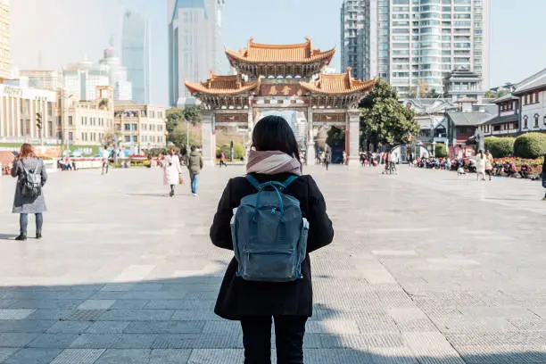 Young woman traveler traveling at Jinbi square, golden Horse and Jade Rooster Archways. landmark and popular for tourists attractions in Kunming, Yunnan, China. Asia and Solo travel concept