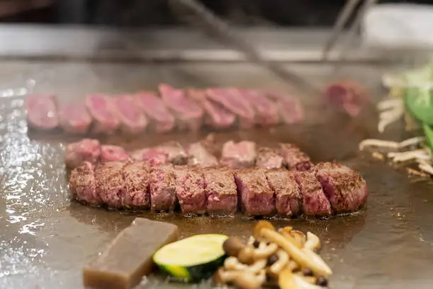 Photo of Kobe beef steak or high quality steak on hot plate pan during Teppanyaki Japanese Chef cooking and grilling in restaurant. Delicious and Popular for tourists attractions in Kobe district, Hyogo, Japan