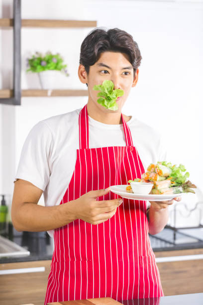 homem asiático come salada no balcão da cozinha. - thai cuisine asian cuisine vertical close up - fotografias e filmes do acervo