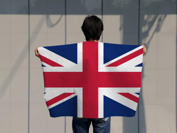 istock The man is holding Union Jack flag on his shoulder and turn back on grey background. 1223554813