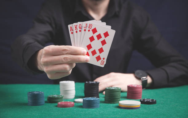 istock Man holding cards with casino chips on the green table. 1223554945