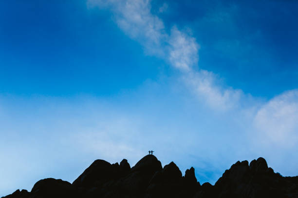 A happy woman rock climbing on a mountain ridge in the Sierra Nevada Mountain Range in California