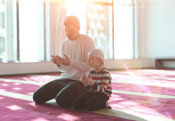 father and son in mosque praying and reading holly book quran together muslim prayer father and son in mosque praying and reading holly book quran together islamic education concept father allah stock pictures, royalty-free photos & images