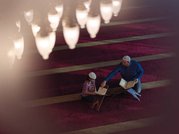 father and son in mosque praying and reading holly book quran together muslim prayer father and son in mosque praying and reading holly book quran together islamic education concept father allah stock pictures, royalty-free photos & images