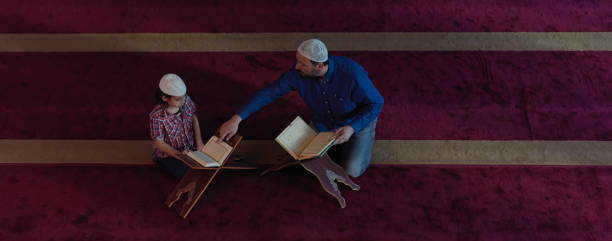 father and son in mosque praying and reading holly book quran together muslim prayer father and son in mosque praying and reading holly book quran together islamic education concept father allah stock pictures, royalty-free photos & images