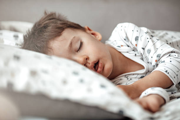 little blond boy sleeping in his bed. - sleeping child bedtime little girls imagens e fotografias de stock