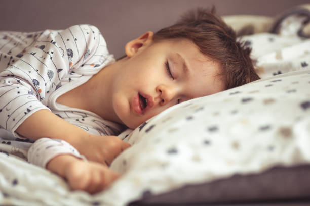 my little boy sleeping by the light of the window. - sleeping child bedtime little girls imagens e fotografias de stock