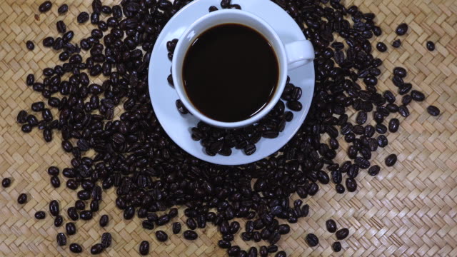 Cup of coffee and coffee beans on wooden background.