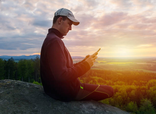 istock Young caucasian man sitting on rock and using his mobile at sunset. Czech republic 1223560318