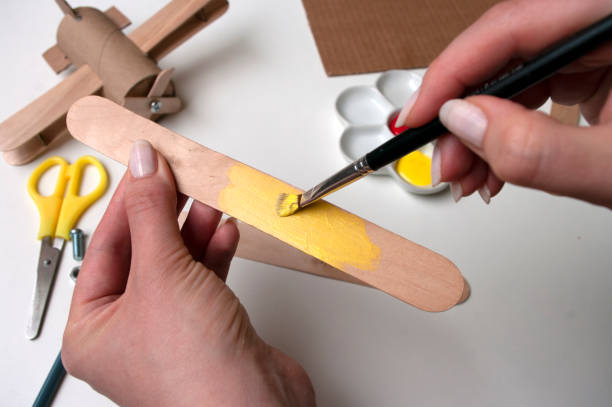 How to make airplane. Hand made toy,zero waste from toilet paper roll and popsicle sticks. For kids and parents.Step 9, wings details paint in yellow. How to make airplane. Hand made toy,zero waste from toilet paper roll and popsicle sticks. For kids and parents. Step 9, wings details paint in yellow. DIY for child, ideas to make during quarantine. popsicle stick stock pictures, royalty-free photos & images