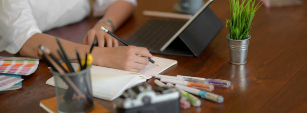 vista lateral de la estudiante universitaria tomar una nota corta en la mesa de madera - art university studio domestic room fotografías e imágenes de stock