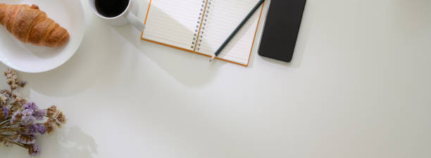 istock Overhead shot of minimal worktable with open blank notebook, smartphone, breakfast meal and copy space 1223562530
