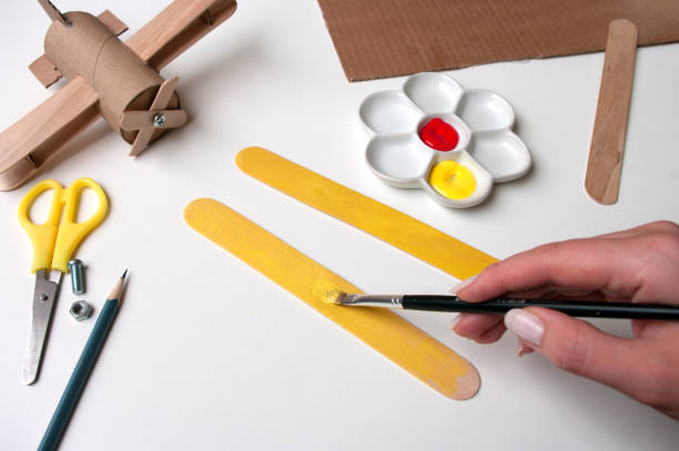How to make airplane. Hand made toy,zero waste from toilet paper roll and popsicle sticks. For kids and parents. Step 10,paint both wings. How to make airplane. Hand made toy,zero waste from toilet paper roll and popsicle sticks. For kids and parents. Step 10,paint both wings. DIY for child, ideas to make during home quarantine. popsicle stick stock pictures, royalty-free photos & images
