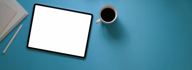 istock Top view of creative workspace with blank screen tablet, coffee cup, diary notebooks and copy space 1223563368
