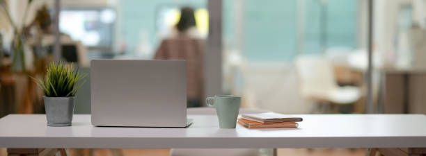 istock Close up view of comfortable office desk with laptop, mug, tree pot, notebooks and copy space on white table 1223563370