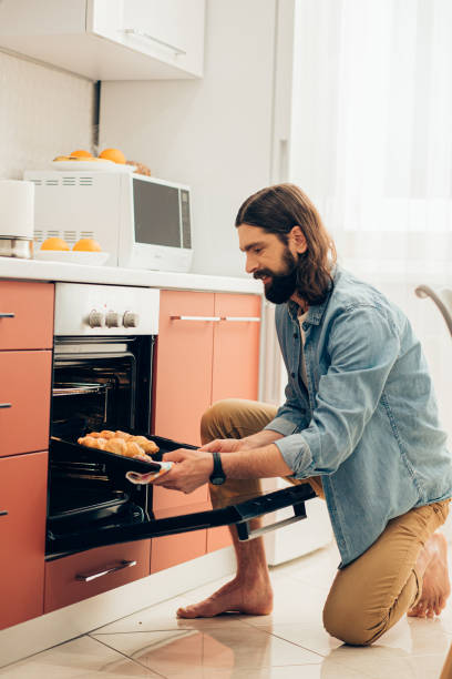 istock Barefooted man in front of the oven with baking pan in hand 1223564505