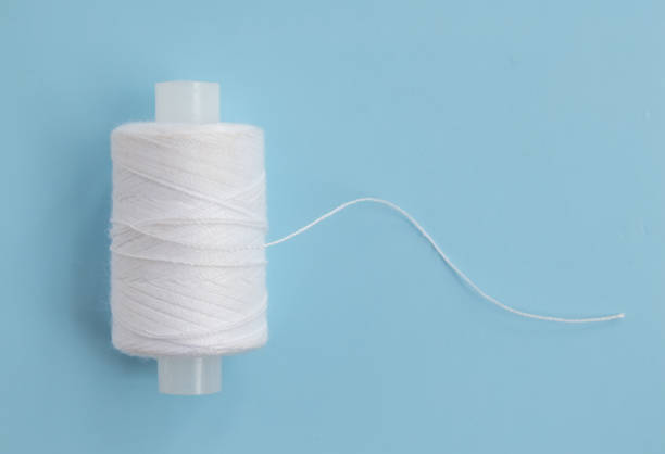 istock Spool of white thread on a blue background close-up. Minimal top view 1223574487