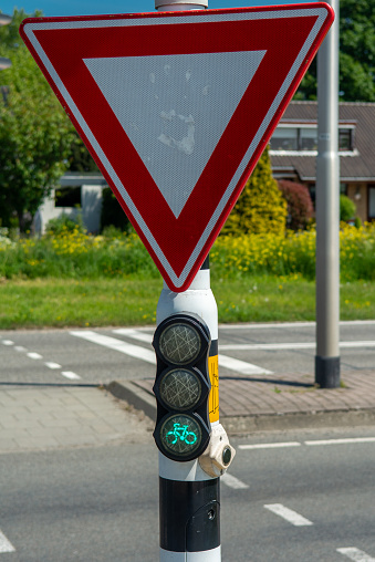 Give way sign with handprint and red bicycle traffic light