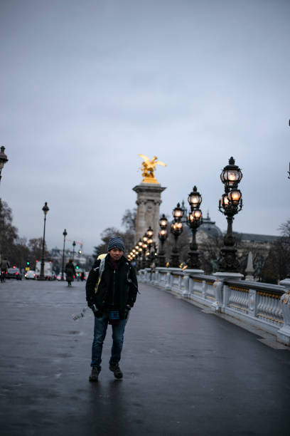Lanterns cast a warm glow along the Seine River as the Eiffel Tower shines in the twilight. Statues adorn the bridge, creating a picturesque Parisian scene during sunset.