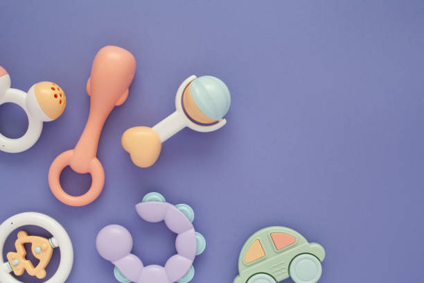 Flat lay composition with baby rattles set in pastel colors and space for text on lilac background. Flat lay composition with stylish baby rattles set in pastel colors and copy space for text on lilac background. First baby toys concept. baby goods stock pictures, royalty-free photos & images