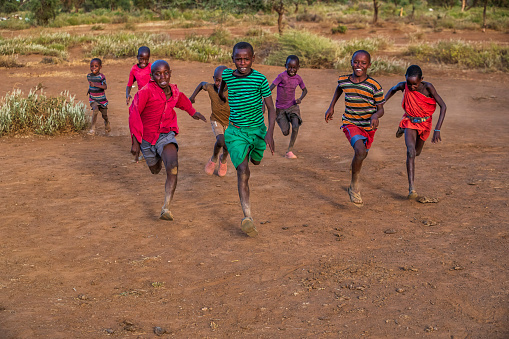 African children from Masai tribe  chasing each other in the village near Mount Kilimanjaro, East Africa, Kenya, East Africa. Maasai tribe inhabiting southern Kenya and northern Tanzania, and they are related to the Samburu.