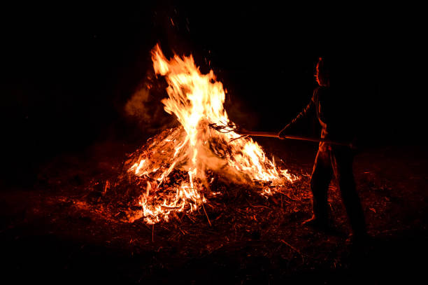 istock A man throws dry leaves into a large fire, night. 1223584312