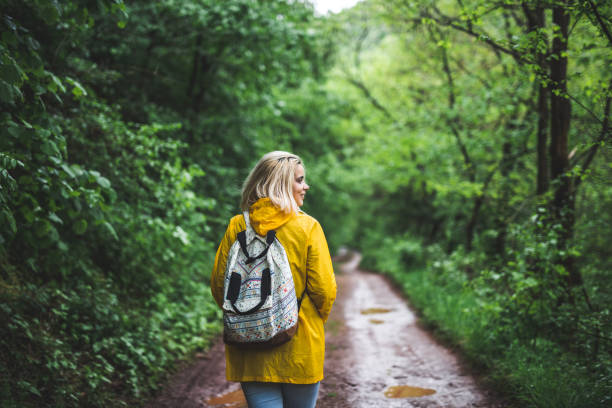 istock Smiling young woman in raincoat walking in forest 1223587026