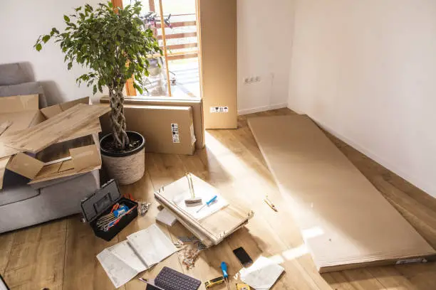 Unassembled flat-pack furniture and tools lying on the floor in a room at home