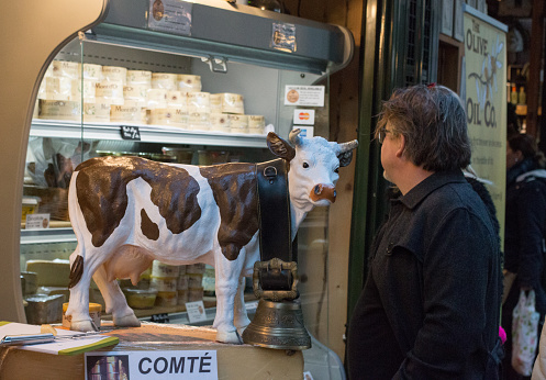 Cow Figurine at a market stall The French Comté in Borough Market, London. A man is seen in the background, shopping.