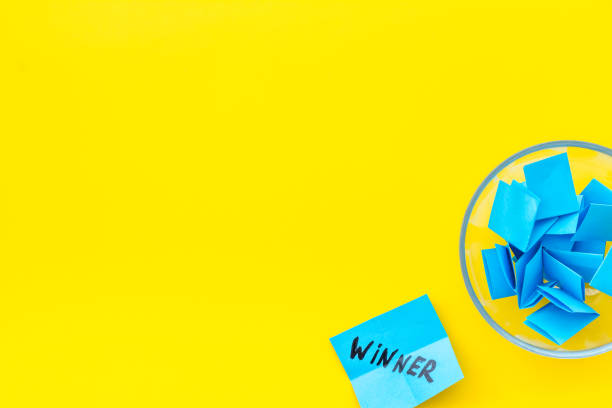 istock Paper pieces - random winner selection - yellow desk top-down copy space 1223587420