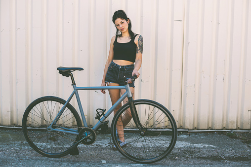 Portrait of a tattooed young woman with bicycle