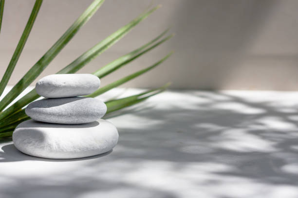 trzy szare okrągłe kamienie i ręczniki kąpielowe na białym tle z zielonymi liśćmi. kamienie spa, zen jak koncepcja. - alternative therapy nature alternative medicine stone zdjęcia i obrazy z banku zdjęć