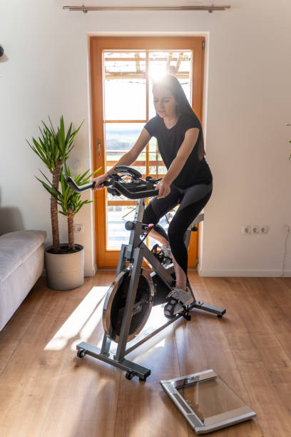 istock Young woman using exercise bike at home 1223590032