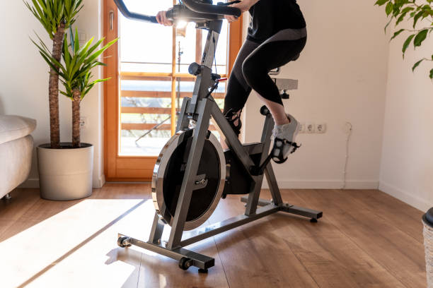 Low section of woman on exercise bike at home Low section view of a young woman in sportswear exercising on exercise bike at home yoga pants photos stock pictures, royalty-free photos & images