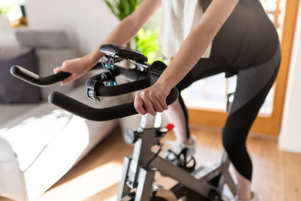 Low section of woman training on exercise bike at home Low section shot of a woman in sportswear exercising on an exercise bike at home yoga pants photos stock pictures, royalty-free photos & images
