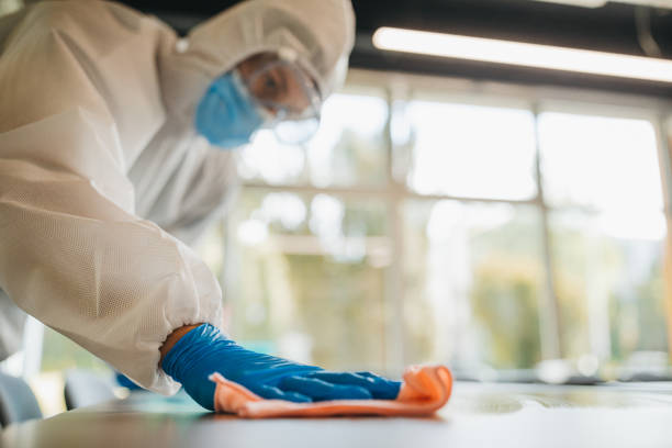 istock Disinfector in a protective suit and mask using disinfectants in office 1223590582