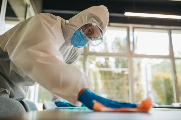 istock Disinfector in a protective suit and mask using disinfectants in office 1223590696