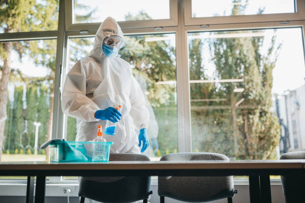 istock Disinfector in a protective suit and mask using disinfectants in office 1223590833