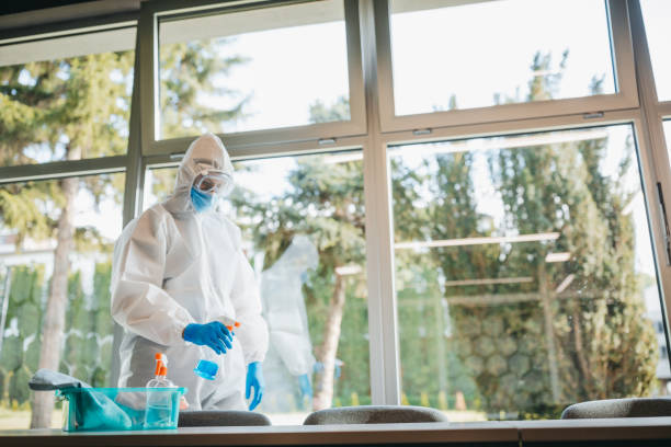istock Disinfector in a protective suit and mask using disinfectants in office 1223590993