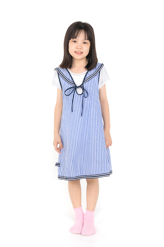 Portrait shot of Asian girl in blue dress standing and smiles to camera on white background.