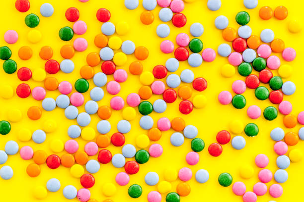 istock Color candy on yellow background top view 1223592896