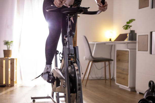 mulher treinando em bicicleta de exercício em casa - pedal bicycle sports training cycling - fotografias e filmes do acervo