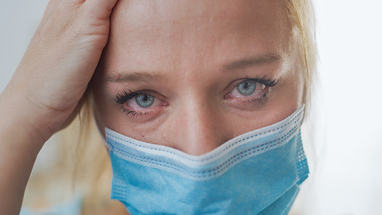 Close up shot of a portrait of a mid adult woman with mask looking at camera in despair and sadness. Conceptual shot of the Coronavirus epidemic.