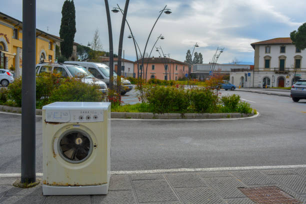 町の歩道にある古い洗濯機。イタリアの路上で違法廃棄物ダンプ家電 - dismembered ストックフォトと画像